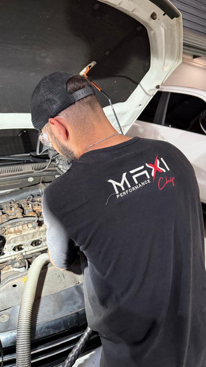 Mecânico da Maxi Chip debruçado sobre motor aberto, com óculos de proteção