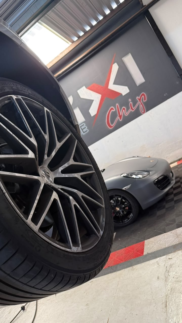 Roda esportiva de Audi com Porsche ao fundo na oficina Maxi Chip